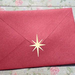 Op de afbeelding: Een rode envelop met een gouden ster sticker op de voorkant.