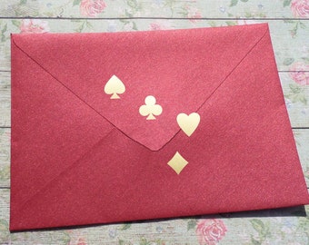 May include: Red envelope with gold glitter and four gold card suit symbols: spade, club, heart, and diamond.