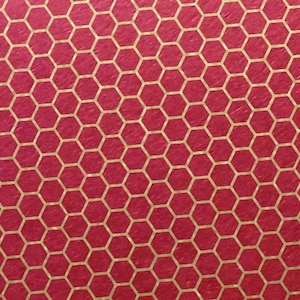 Puede incluir: Un fondo rojo con un patrón de panal de abeja dorado.