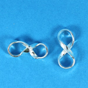 May include: Two silver infinity symbol charms on a blue background.