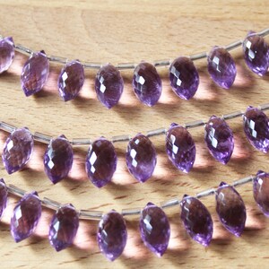 May include: Three strands of amethyst gemstone beads, each strand featuring a row of faceted, teardrop-shaped beads strung on silver wire.