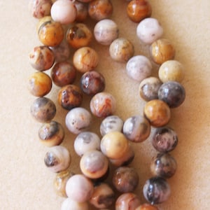 May include: A strand of brown, white and grey agate beads. The beads are round and have a natural, polished finish.