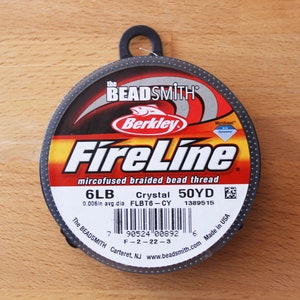May include: A spool of FireLine microfused braided bead thread. The label is black, red, and yellow, with the brand name "Berkley" and "The Beadsmith" visible. The spool contains 45.72 metres of 6LB crystal thread.
