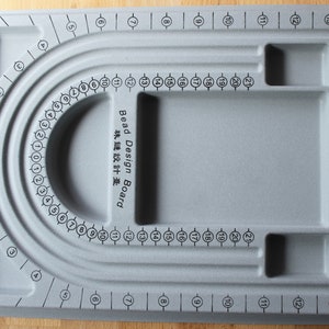 May include: Grey bead design board with a U-shaped groove and multiple compartments. The board is labelled "Bead Design Board" and "珠鏈設計臺".
