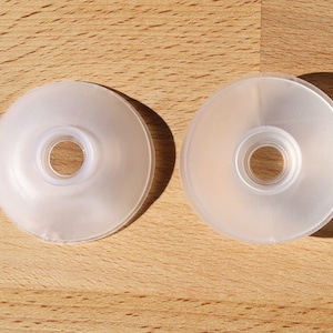 May include: Two clear plastic round discs with a central hole. The discs are slightly raised in the centre.