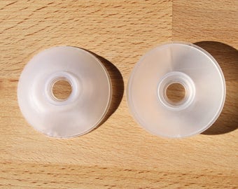 May include: Two clear plastic round discs with a central hole. The discs are slightly raised in the centre.