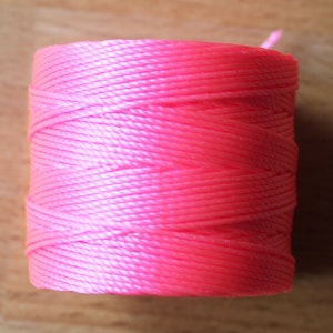 May include: A spool of bright pink cord, ideal for crafting projects.
