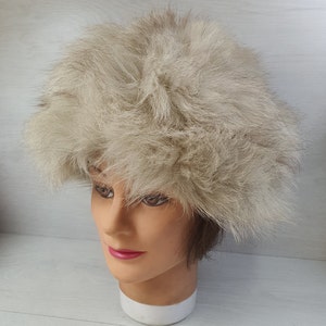 May include: A fluffy white fur hat with a wide brim. The hat is made of real fur and has a soft, luxurious feel.
