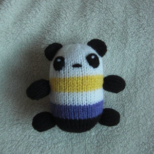 May include: A knitted panda plush toy with black ears, eyes, and limbs. The body is white with yellow, purple, and black stripes.