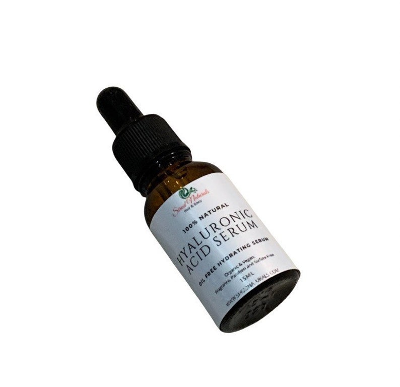 May include: A brown glass bottle with a dropper top containing Hyaluronic Acid Serum. The bottle is labeled with white text that reads "100% Natural Hyaluronic Acid Serum Oil Free Hydrating Serum Organic & Vegan Paraben and Sulfate Free 15ML".