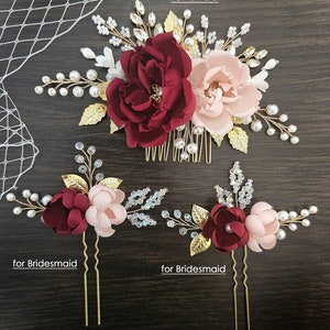 May include: Set of three burgundy and blush floral hair combs with gold accents and pearl embellishments. The larger comb is for a bride and the two smaller combs are for bridesmaids. "Set of 3" is written in the top right corner of the image. "for Bride" is written in the top center of the image. "for Bridesmaid" is written in the bottom left corner of the image. "for Bridesmaid" is written in the bottom right corner of the image.