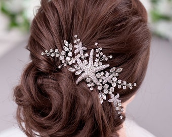 May include: A silver hair comb with a starfish design and rhinestones. The comb is in a woman's brown hair.