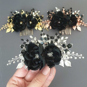 Op de afbeelding: Drie zwarte bloemenhaar-kammen met zilveren, gouden en ros&eacute;gouden accenten. Elke kam heeft twee zwarte stoffen bloemen met strass steentjes en zwarte kralen.