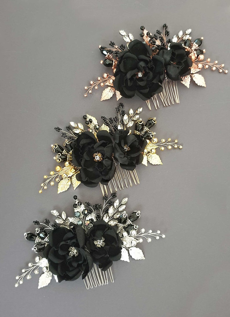 Puede incluir: Tres peinetas florales negras con detalles dorados, plateados y negros. Cada peineta presenta flores de tela, adornos de cuentas y detalles de hojas met&aacute;licas. Las peinetas est&aacute;n dispuestas sobre un fondo gris.