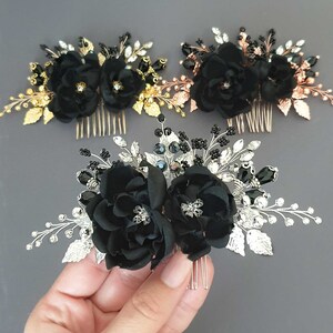 Puede incluir: Tres peinetas florales con flores de tela negra y detalles decorativos. Una peineta tiene hojas y detalles dorados, otra tiene oro rosa y la tercera tiene detalles plateados. Las peinetas est&aacute;n sobre un fondo gris.
