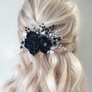 Puede incluir: Un peine para el cabello floral negro con dos rosas de tela, hojas plateadas y detalles de cristal negro y transparente. El accesorio para el cabello est&aacute; dise&ntilde;ado para ocasiones formales y a&ntilde;ade elegancia.
