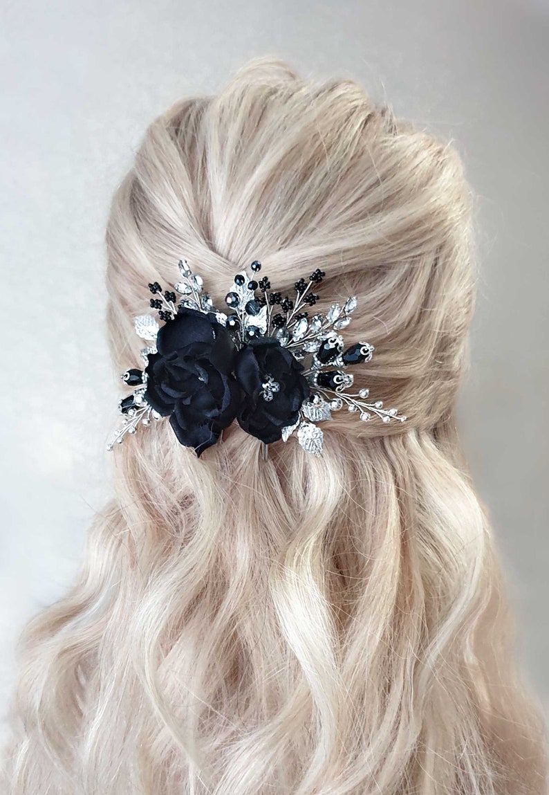 Puede incluir: Un peine para el cabello floral negro con dos rosas de tela, hojas plateadas y detalles de cristal negro y transparente. El accesorio para el cabello est&aacute; dise&ntilde;ado para ocasiones formales y a&ntilde;ade elegancia.