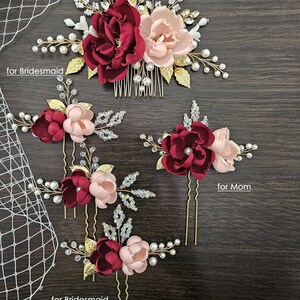 May include: Set of five burgundy and blush floral hair combs and pins. The set includes a larger comb with a burgundy and blush flower, a smaller comb with a burgundy and blush flower, and three pins with burgundy and blush flowers. The text "Set of 5" is visible in the top right corner of the image. The text "for Bride" is visible in the top left corner of the image. The text "for Bridesmaid" is visible in the bottom left corner of the image. The text "for Mom" is visible in the bottom right corner of the image.