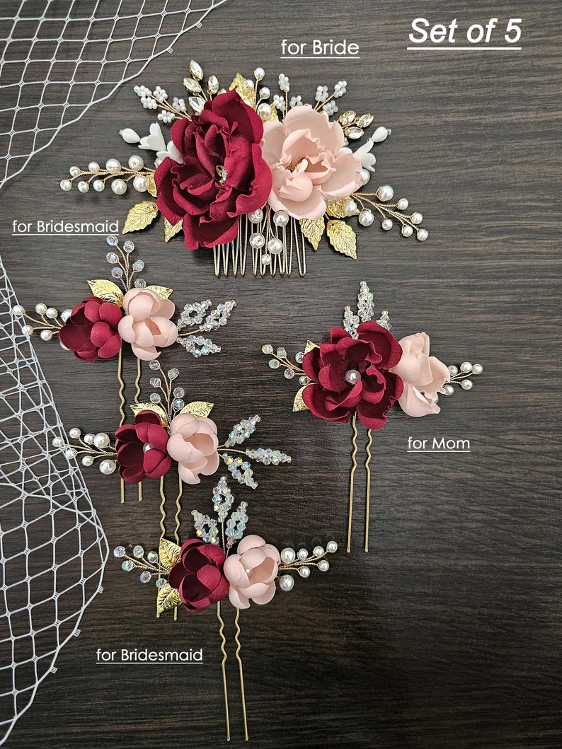 May include: Set of five burgundy and blush floral hair combs and pins. The set includes a larger comb with a burgundy and blush flower, a smaller comb with a burgundy and blush flower, and three pins with burgundy and blush flowers. The text "Set of 5" is visible in the top right corner of the image. The text "for Bride" is visible in the top left corner of the image. The text "for Bridesmaid" is visible in the bottom left corner of the image. The text "for Mom" is visible in the bottom right corner of the image.