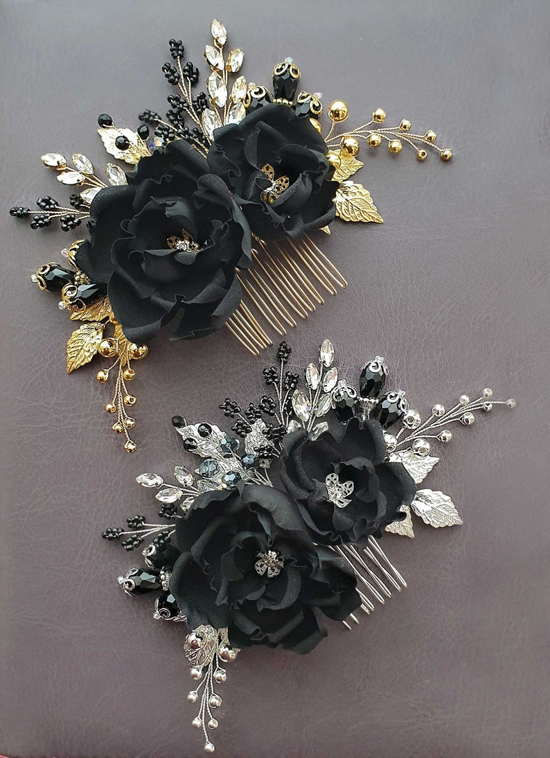 Op de afbeelding: Twee zwarte bloemen haar kammen met gouden en zilveren versieringen. Elke kam is versierd met zwarte bloemen van stof, strass steentjes en kralen.