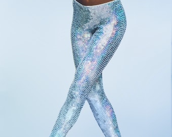 May include: A pair of iridescent blue leggings with a sequined pattern. The leggings are worn by a person with dark skin and are shown against a light blue background.
