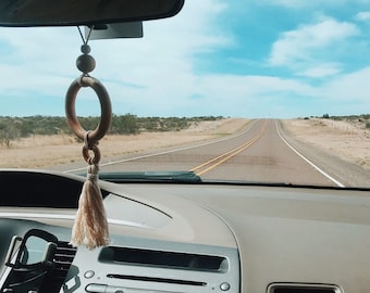 May include: A view from the driver's seat of a car on a long, straight road. The sky is blue with white clouds. The person's feet are resting on the dashboard, wearing pink slip-on shoes and blue jeans.