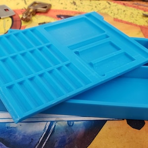 May include: A blue plastic storage box with a lid. The lid has multiple compartments for organising small items. The box is open and the lid is resting on top.