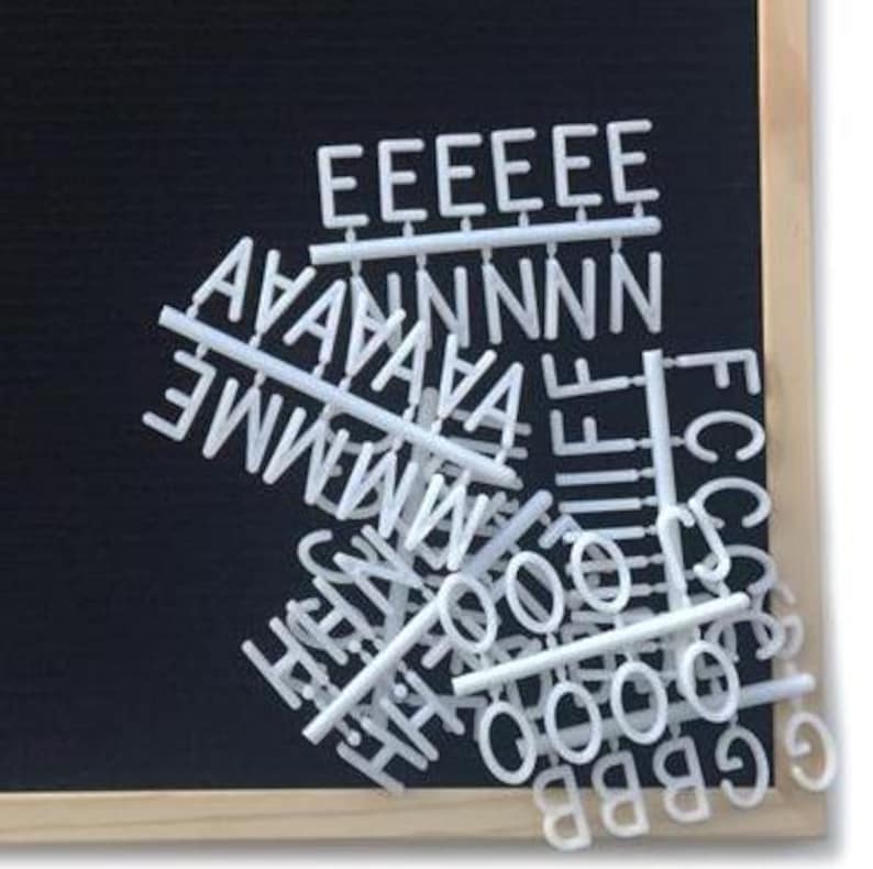 May include: White plastic letters and numbers on a black chalkboard background. The letters are arranged in a random pattern and include the letters E, A, N, M, H, I, F, O, C, G, S, and B.