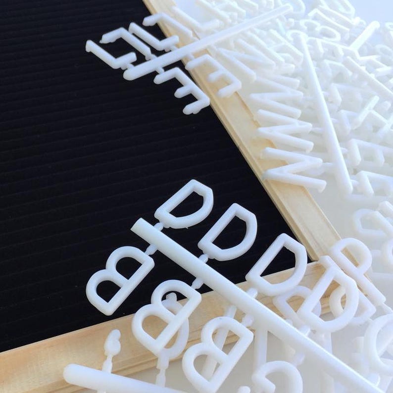 May include: White plastic letters and numbers on a wooden frame. The letters are arranged in a random order and are ready to be used for a message board.