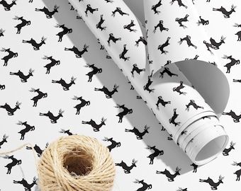 May include: White wrapping paper with a repeating pattern of black reindeer silhouettes. A ball of twine is in the foreground.