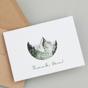Może przedstawiać: Biała kartka z akwarelową ilustracją pasma górskiego w kółku. Tekst "Thank You!" jest napisany na zielono pod ilustracją.