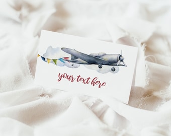 May include: A printable card with a watercolor illustration of a vintage airplane flying through the clouds with a string of colorful flags. The text "your text here" is written in red below the airplane.