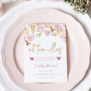 May include: A pink and gold floral themed invitation card with the text "Oh Two-dles" in gold lettering. The text "It's hard to believe, but yes it's true our Emmalyn is turning 2!" is written in pink lettering. The invitation includes details for a birthday party, including the date, time, location, and RSVP information.