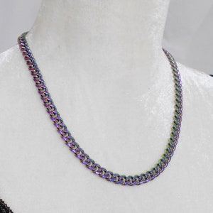 Op de afbeelding: Een zilveren ketting met een regenboogkleurige, iriserende afwerking. De ketting is van het curb-type.