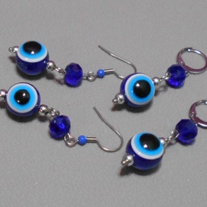 May include: A pair of earrings with blue evil eye charms and blue crystal beads. The earrings have silver hooks.