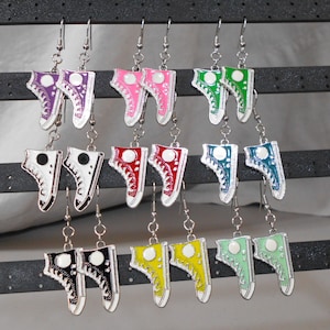 May include: A set of 10 pairs of dangle earrings featuring a variety of colors and designs. Each earring features a small shoe charm with a different color and design. The earrings are made of metal and are perfect for adding a touch of whimsy to any outfit.