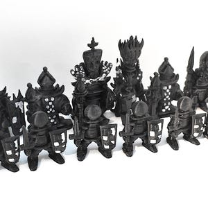 May include: A collection of 15 black plastic miniature figures of knights and warriors. The figures are all wearing armor and holding weapons. Some of the figures are wearing crowns.