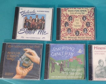 Könnte beinhalten: Fünf CDs von The Wholesale Klezmer Band. Zu den Titeln gehören "Shmir Me", "Yidn Fun Amol", "Prayer for a Broken World", "Sing for Peace Dance for Joy" und "Hineni". Die CDs befinden sich in transparenten Kunststoffhüllen.