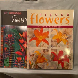 Könnte beinhalten: Zwei Quiltbücher mit dem Titel "Pieced Flowers" von Ruth B. McDowell. Der Buchumschlag zeigt vier verschiedene Blumendesigns in Orange-, Gelb- und Rottönen.