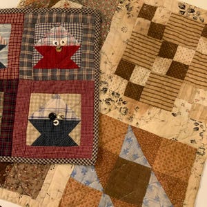 May include: Close-up of several handmade quilts with various patterns and colors. One quilt features a red and blue starburst design, while another has a patchwork of squares in shades of brown and cream. The quilts are made of fabric with plaid, floral, and geometric patterns.
