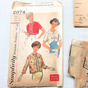 May include: Vintage Simplicity sewing pattern packet, featuring illustrations of women's jackets and tops. The packet includes a primer and pattern pieces. The main packet is labeled "2974" and "Printed Pattern 40¢".
