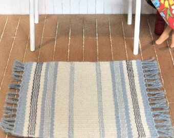 Handmade miniature dollhouse rug. Handwoven mug rug or blue doll house rug in striped flat woven weft face pattern. Wool. 5" by 7.5" overall