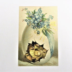 May include: Vintage Easter postcard featuring a cracked egg with four yellow chicks inside. A bouquet of blue flowers and a blue ribbon adorn the top of the egg. The postcard has a soft, pastel color palette.
