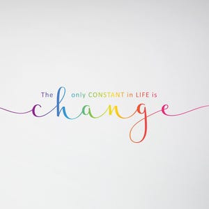 May include: A white wall with the rainbow text "The only CONSTANT in LIFE is change" in a cursive font. A beige mug sits on a white desk with a wooden chair in the foreground. A lamp with a gray shade is on the left.