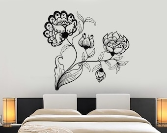 May include: Black and white floral wall decal with a stylized design of flowers and leaves. The decal is applied to a white wall behind a black bed frame with white bedding.