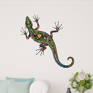 May include: A colorful lizard wall decal with intricate patterns in green, orange, yellow, and blue. The lizard is depicted with its legs outstretched, and its tail is curled. The decal is applied to a white wall, creating a vibrant accent.