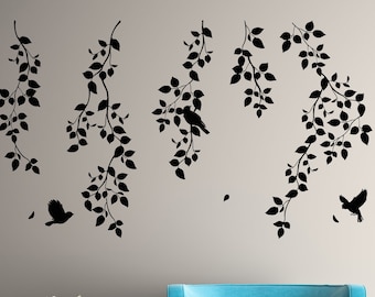 May include: A teal blue armchair with wooden legs sits in front of a gray wall with black silhouette wall decals of branches and birds.
