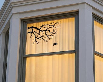 May include: A white house with a bay window. The window has a sheer curtain and a black silhouette of a tree branch with a bat hanging from it.