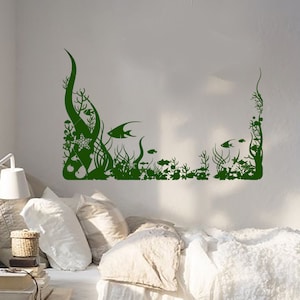 Puede incluir: Una calcomanía de pared verde que presenta una silueta de una escena submarina con algas marinas, corales y peces. La calcomanía es perfecta para agregar un toque de fantasía a la habitación de un niño o una sala de juegos.