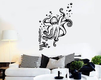 May include: Black and white wall decal of an octopus with tentacles outstretched, surrounded by bubbles. The octopus is swimming upwards towards the top of the image. The decal is on a white wall in a living room setting.